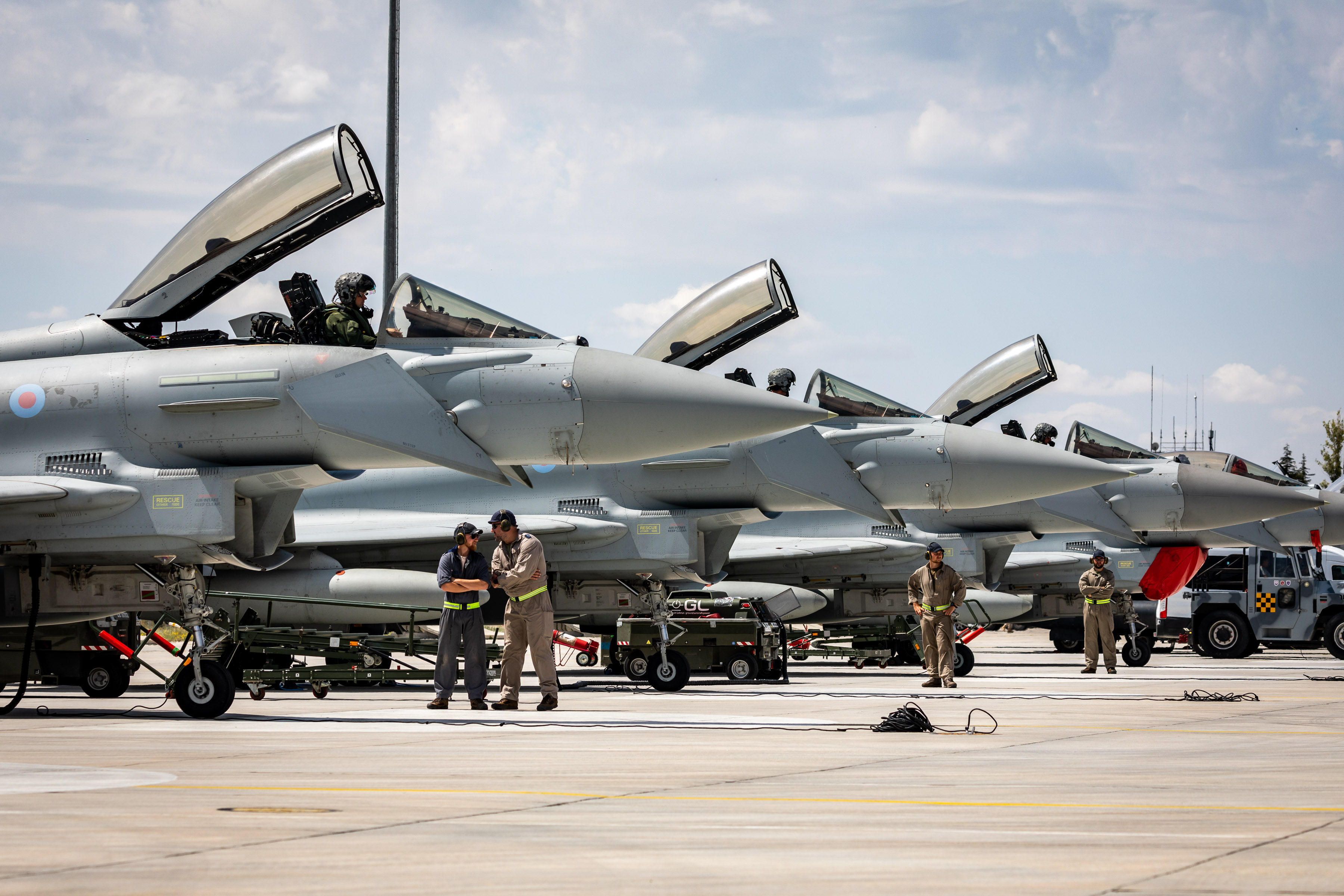 Image shows aviators standing by row of Typhoon aircraft on the airfield.